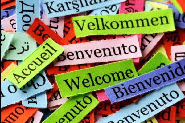 Photo of cut up pieces of paper displaying "Welcome" in languages from all around the world.