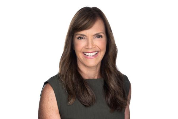 Headshot of Lynn Lyons, a Caucasian woman with shoulder length brown hair wearing a sleeveless gray top.