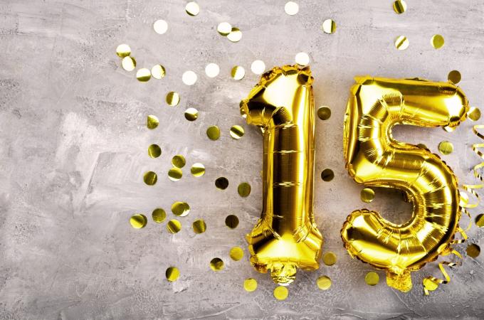 Photograph of helium filled gold 1 and 5 balloons with gold sparkly confetti surrounding them